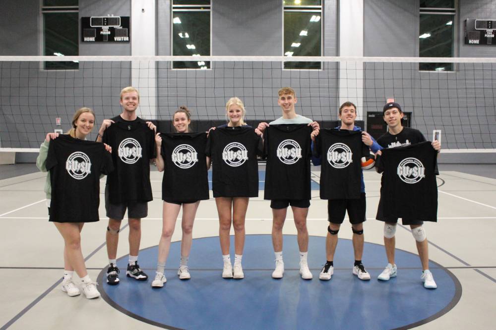 Students holding up championship shirts from an upper bracket volleyball tournament